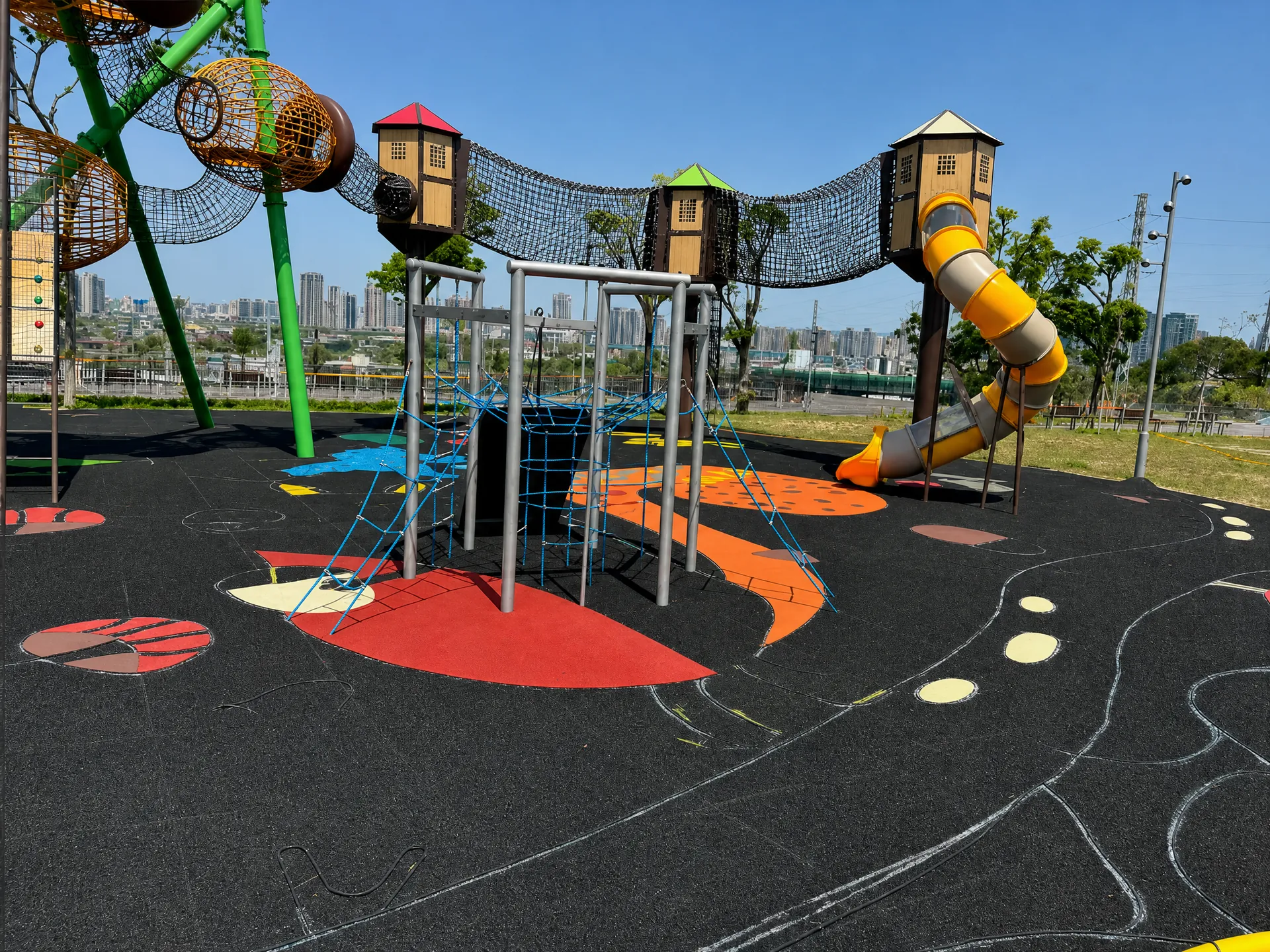 Modern playground with colorful rubber surfacing and climbing towers