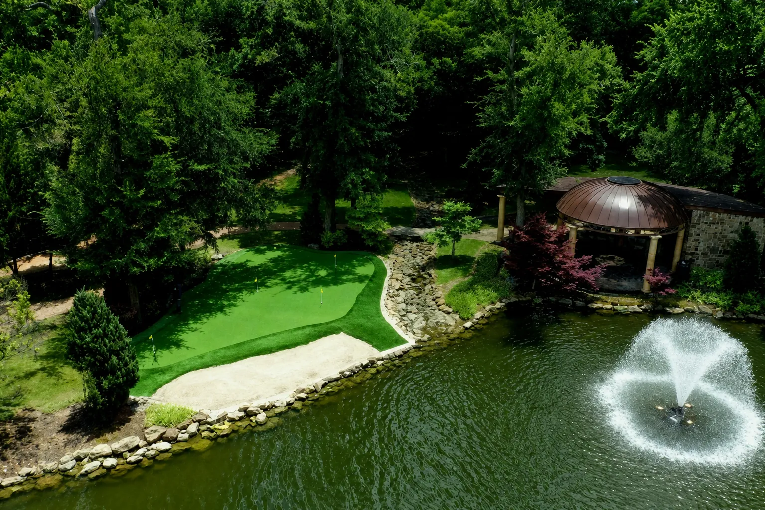 Putting green by pond with fountain and gazebo